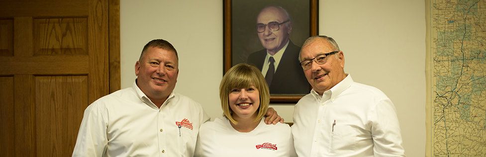 Steve Buck, Delanie Baustert and Lowell Buck with a portrait of founder Howard Buck